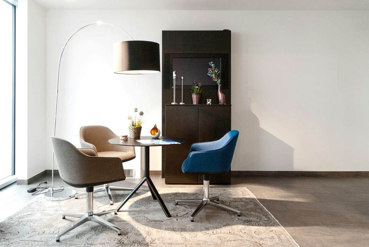 Beratungsecke mit zwei Sesseln, Bogenlampe und Sideboard